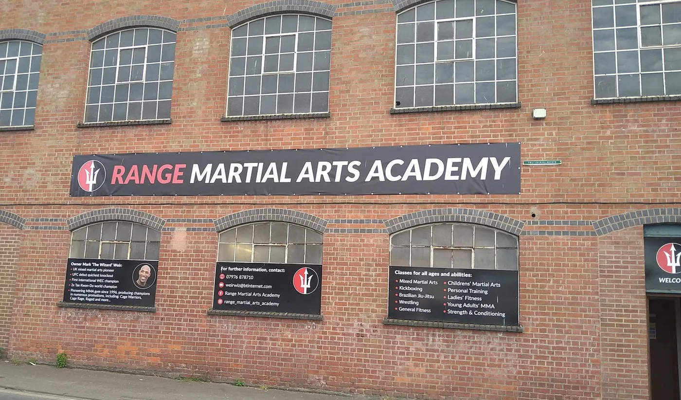 The brick frontage of Range Martial Arts Academy on Bristol Road, Gloucester, with the academy’s banner and signs beside the door